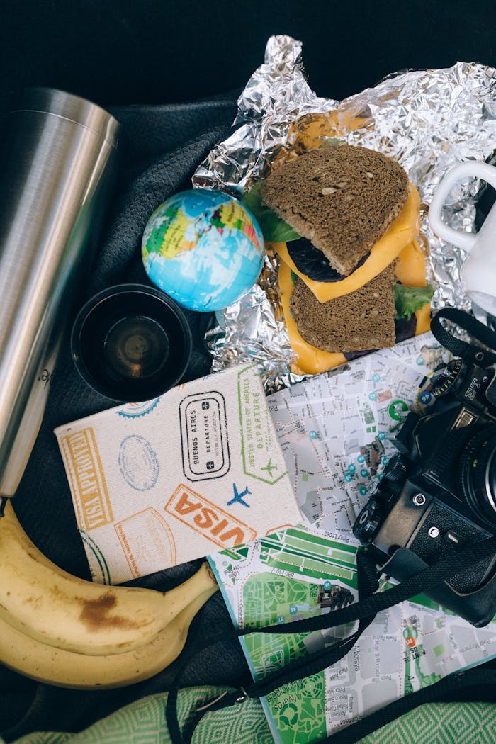 Flat lay of travel essentials with camera and snacks, perfect for a journey.